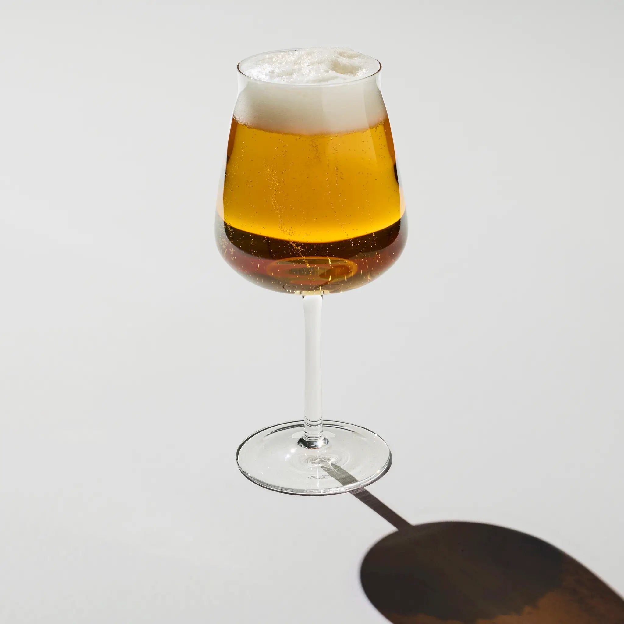 Et Brewer’s Tower Glass fyldt med lys øl – elegante, høje glas med skumkrone og klar farve, designet til en raffineret øloplevelse.