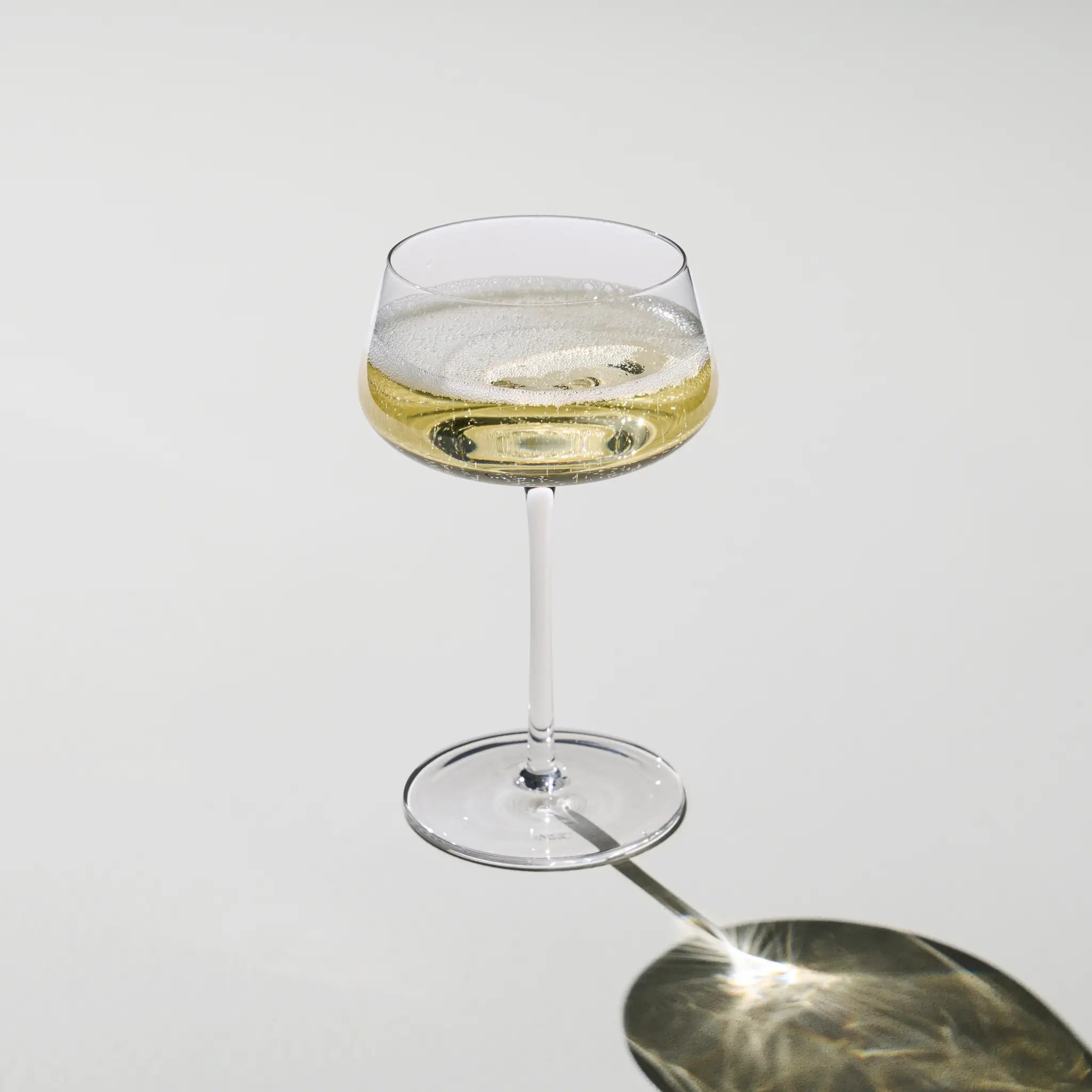 Sæt med 2 Beyond Bubbly Coupe-glas fyldt med champagne – elegante coupeglas, der fremhæver bobler og aromaer med raffineret stil.